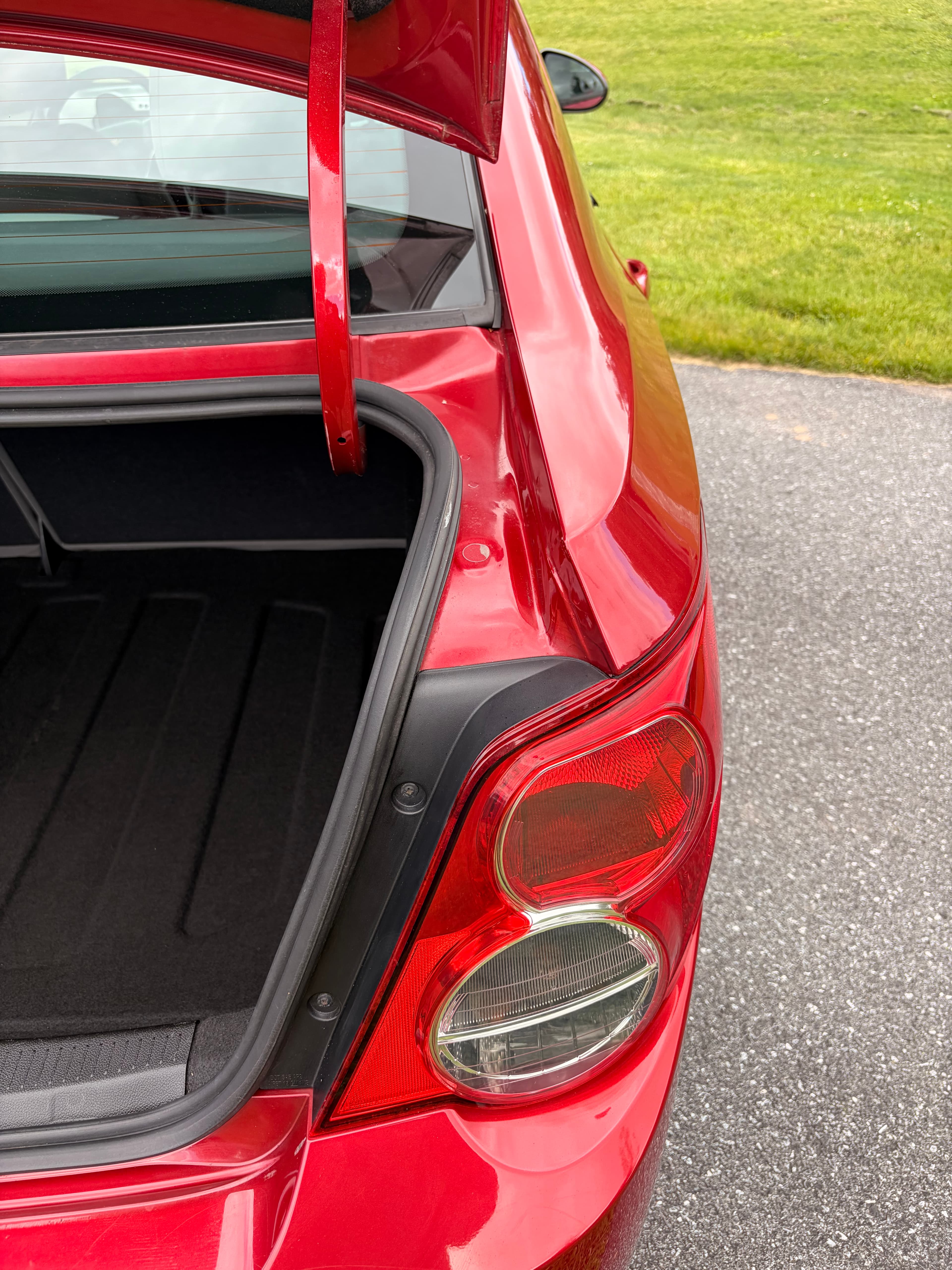 Red car with an open trunk, showing the taillight assembly and black interior lining.