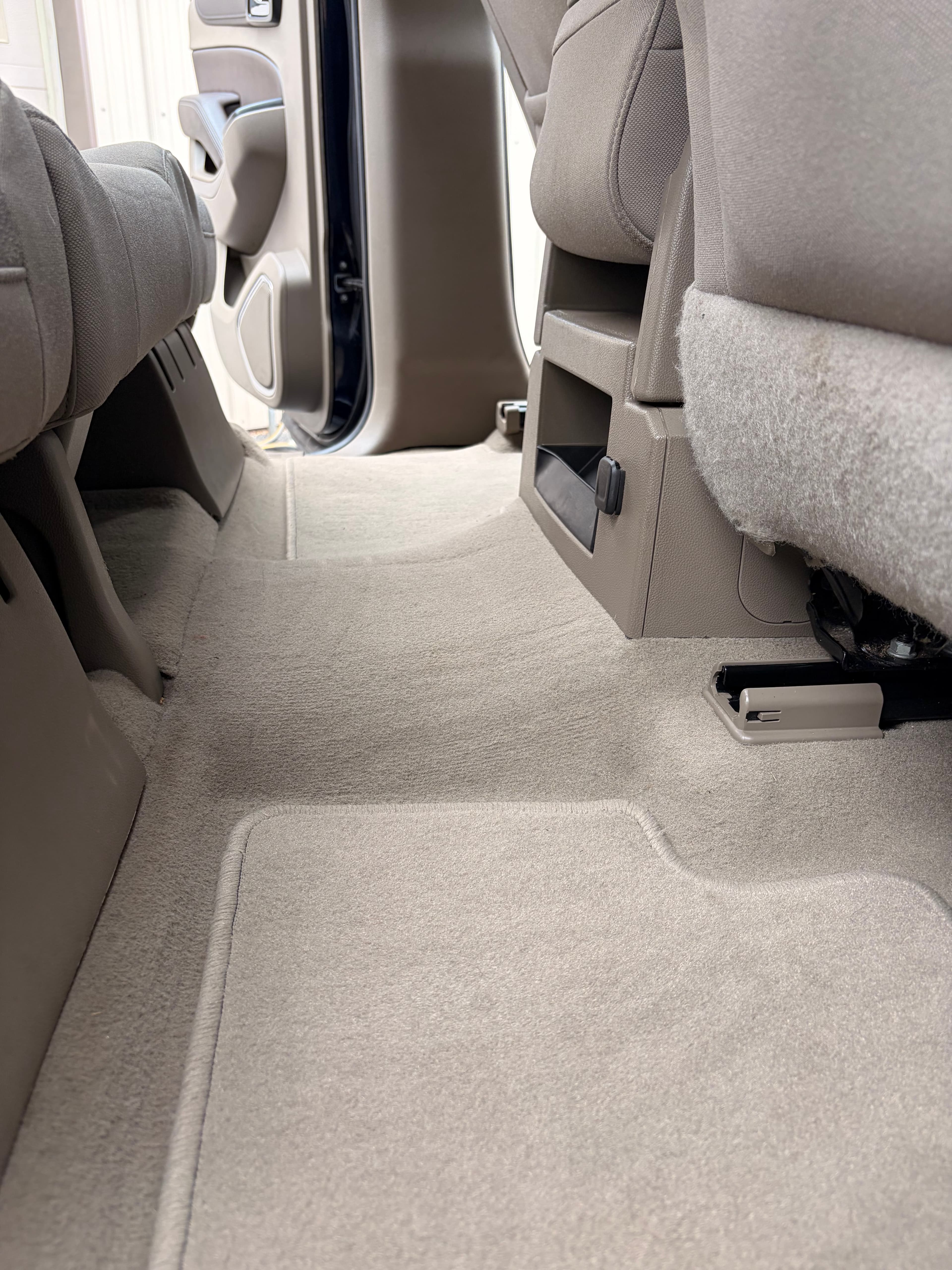 Clean tan carpeting and floor mats in the rear passenger area of a modern vehicle interior.