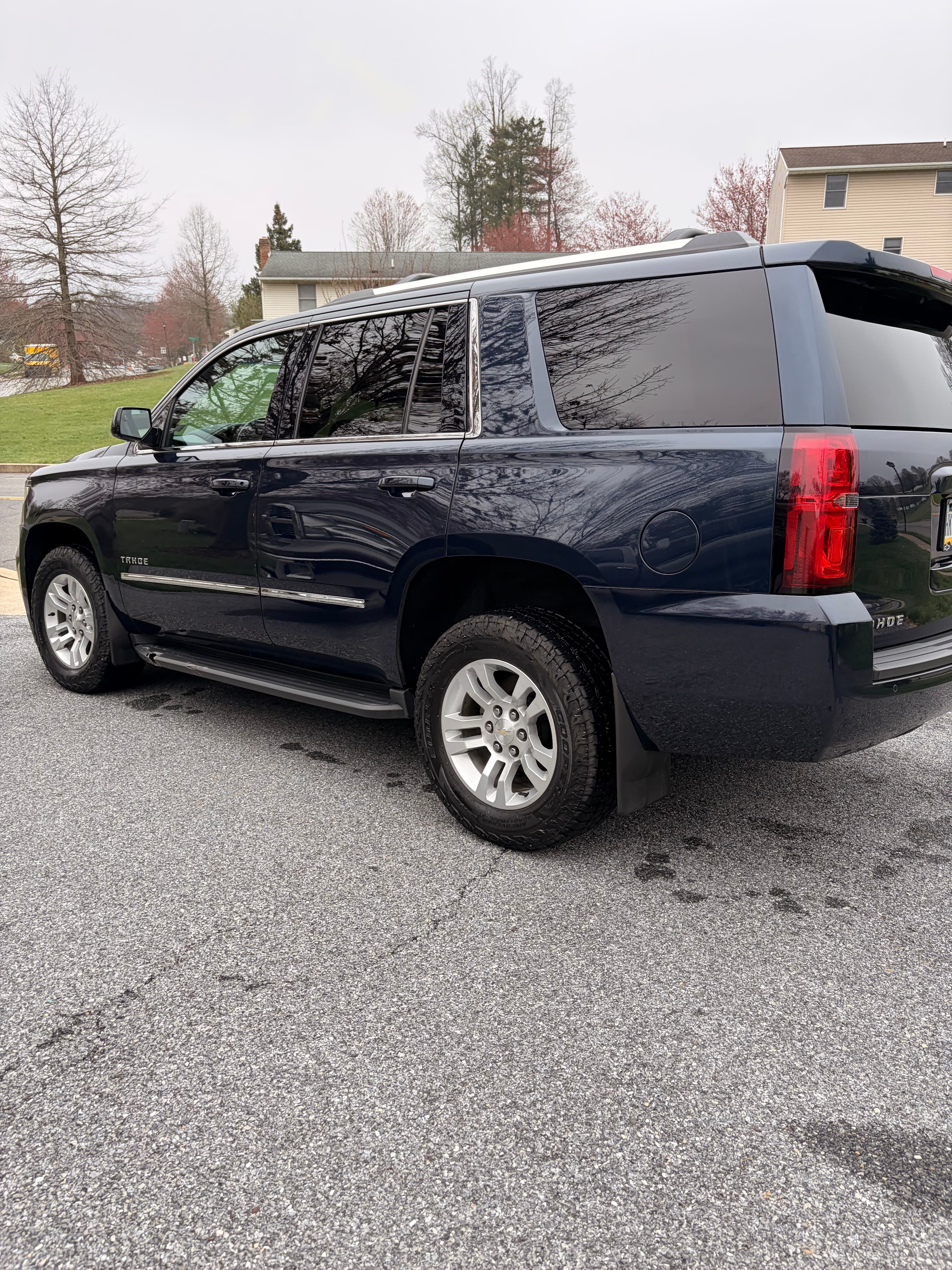 Dark blue Chevrolet Tahoe SUV parked on an asphalt driveway in a residential neighborhood.