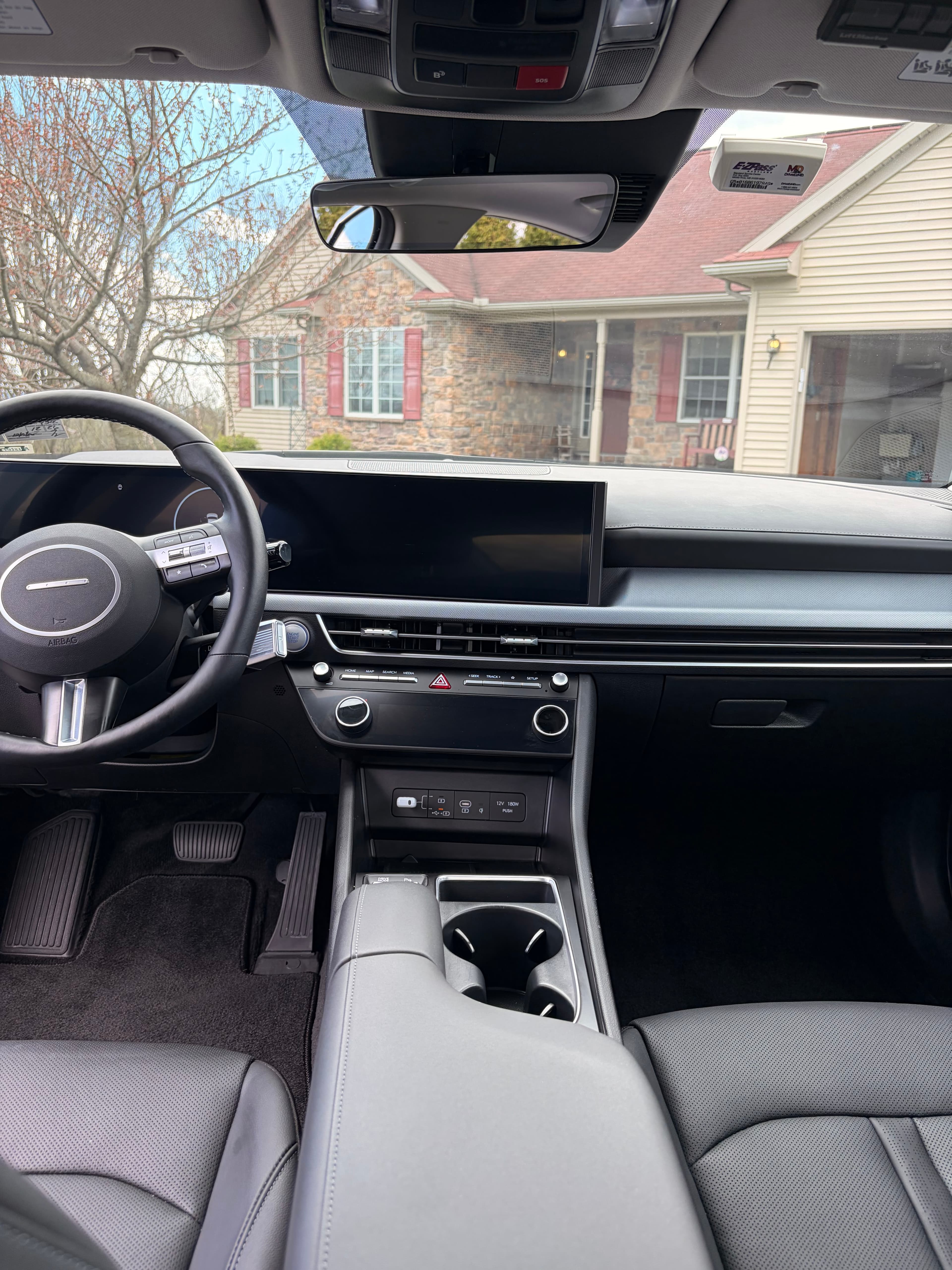 Modern car interior featuring a large digital dashboard, steering wheel, and grey leather seats.